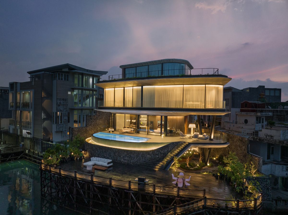 An evening view of the house from the water showcases its glowing interiors