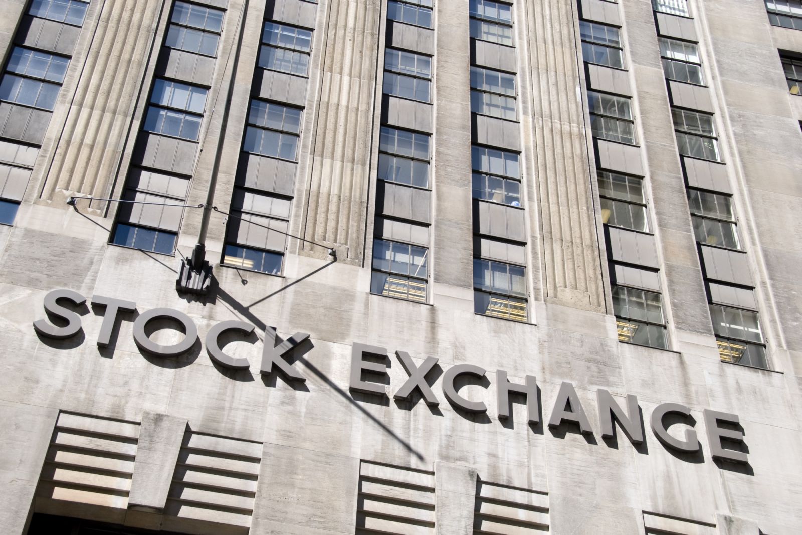 Low angle view of the Stock Exchange sign on the facade of the New York Stock Exchange on Wall street, Manhattan. The NYSE is the heart of the financial district in New York City.