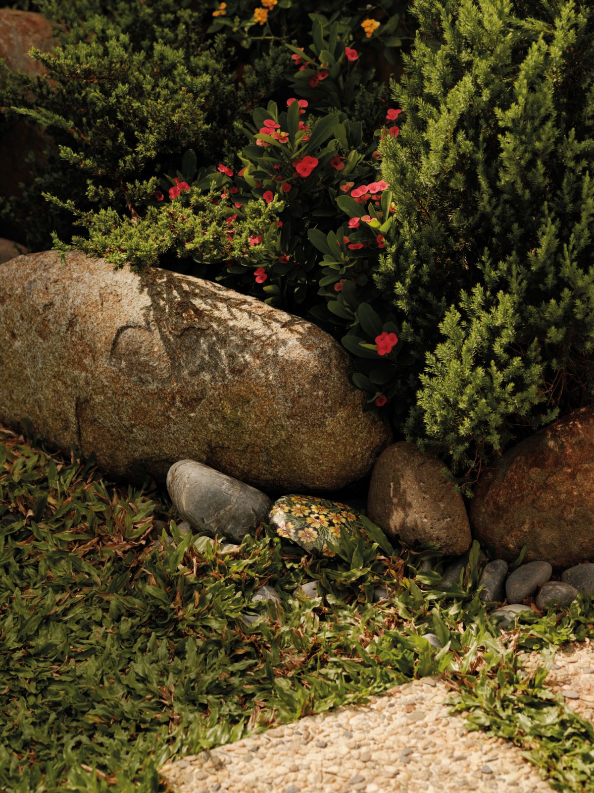 Nestled among the garden’s curated plants and natural rocks is a delightful painted pebble, also an artwork by the owner