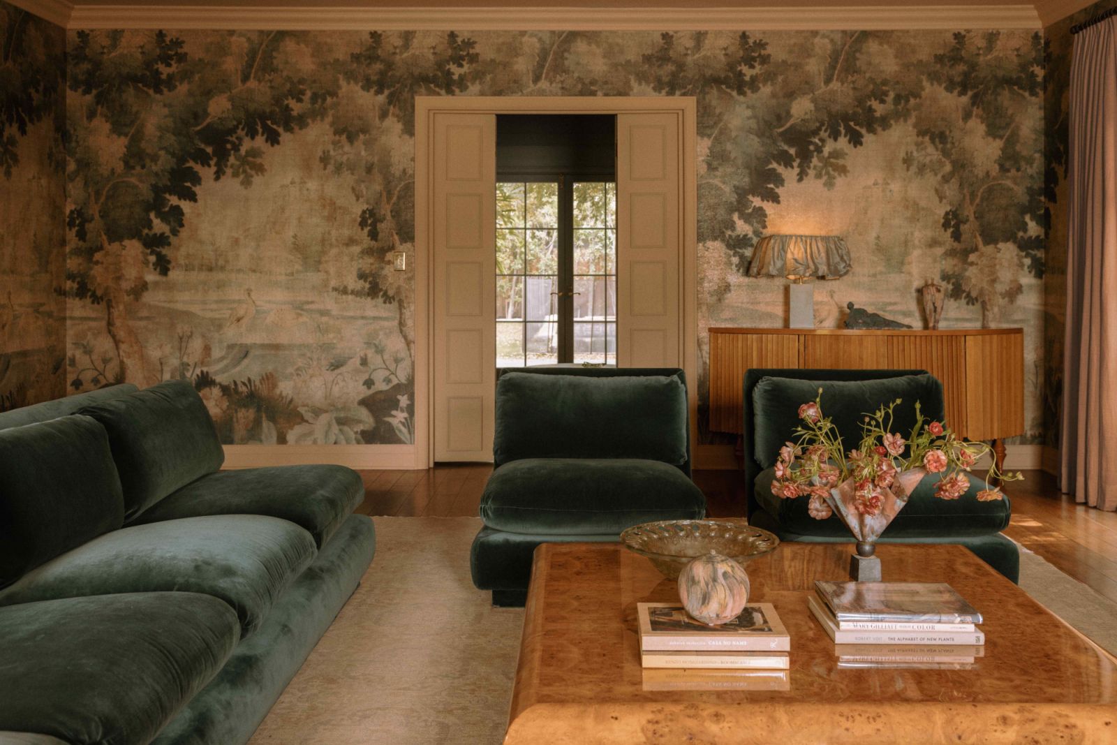 Green velvet sofas complement the textured mural wallpaper by Pierre Frey