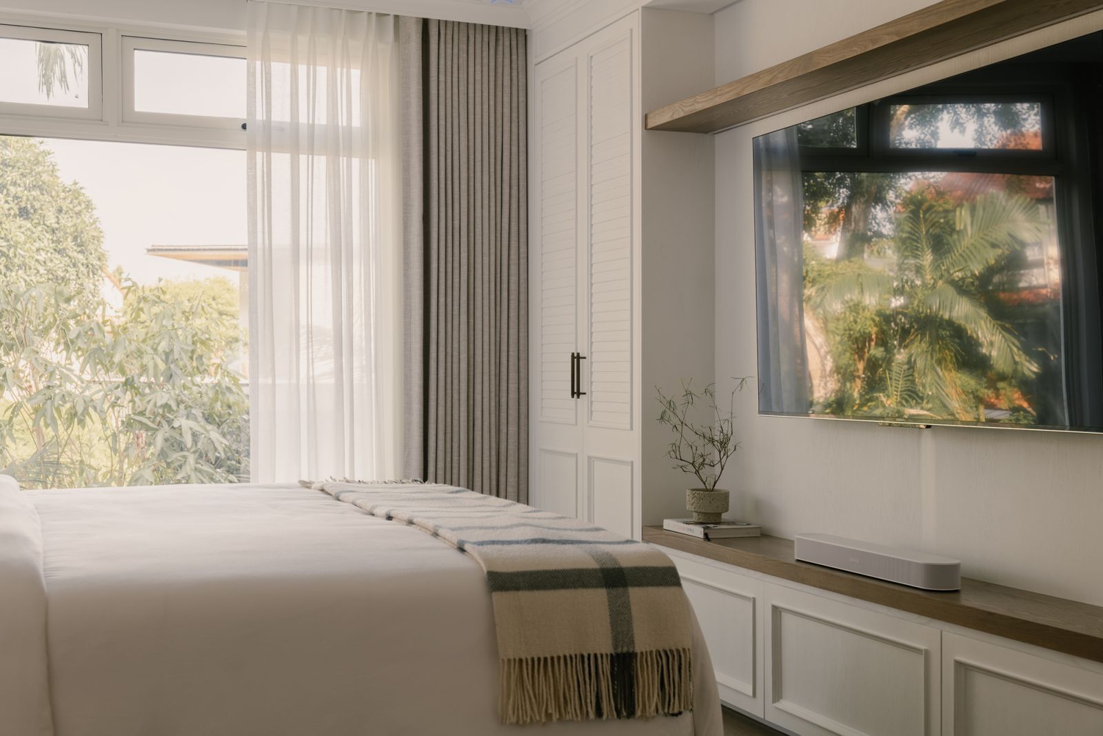 Verdant outdoor greenery forms a living backdrop in the master bedroom