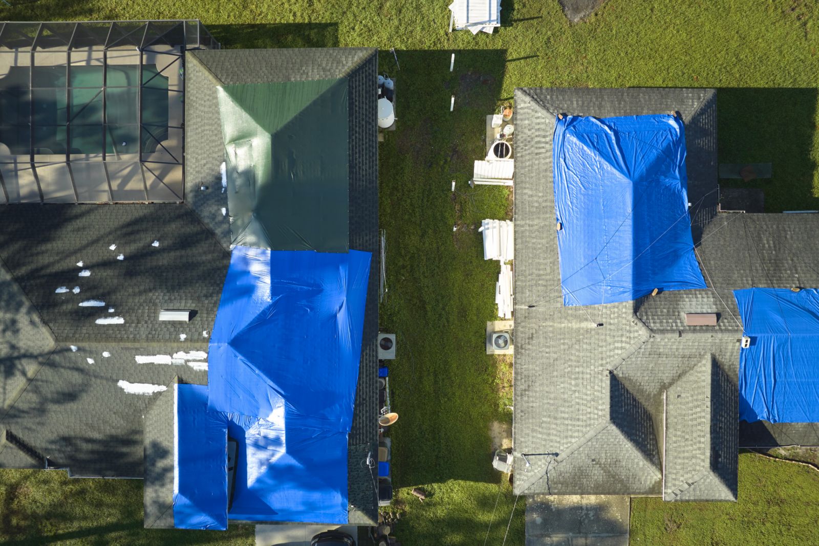 Aerial view of damaged in hurricane Ian house roof covered with blue protective tarp against rain water leaking until replacement of asphalt shingles (Photo: Getty Images)