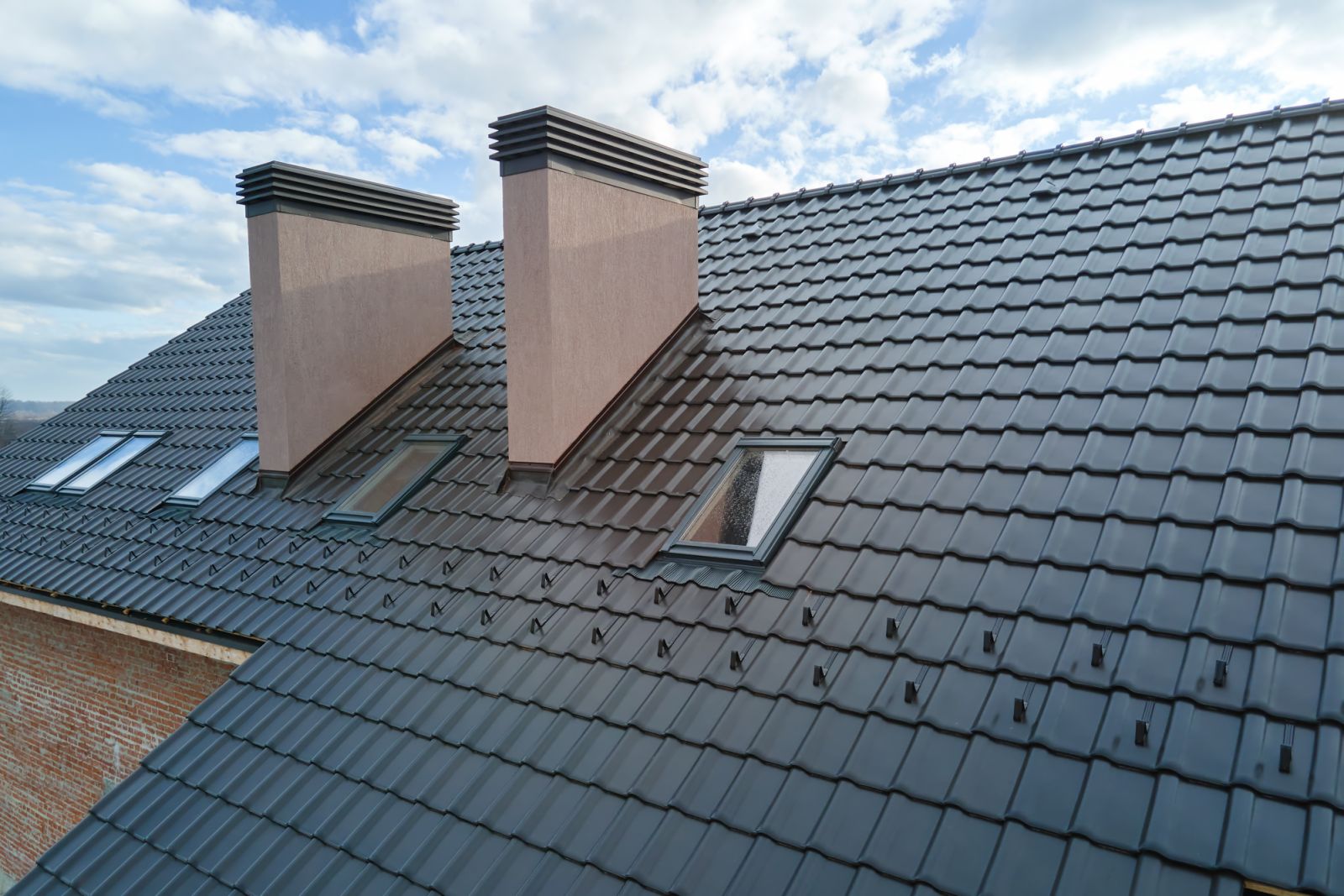 Closeup of attic windows and brick chimneys on house roof top covered with ceramic shingles (Photo: Getty Images)