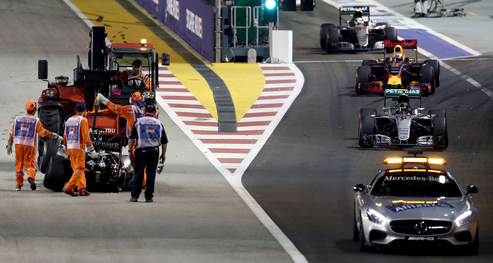 SINGAPORE - SEPTEMBER 18: The safety car leads Nico Rosberg of Germany driving the (6) Mercedes AMG Petronas F1 Team Mercedes F1 WO7 Mercedes PU106C Hybrid turbo, Daniel Ricciardo of Australia driving the (3) Red Bull Racing Red Bull-TAG Heuer RB12 TAG Heuer Lewis Hamilton of Great Britain driving the (44) Mercedes AMG Petronas F1 Team Mercedes F1 WO7 Mercedes PU106C Hybrid turbo and the rest of the field through the pit lane past the remains of the crash of Nico Hulkenberg of Germany and Force India during