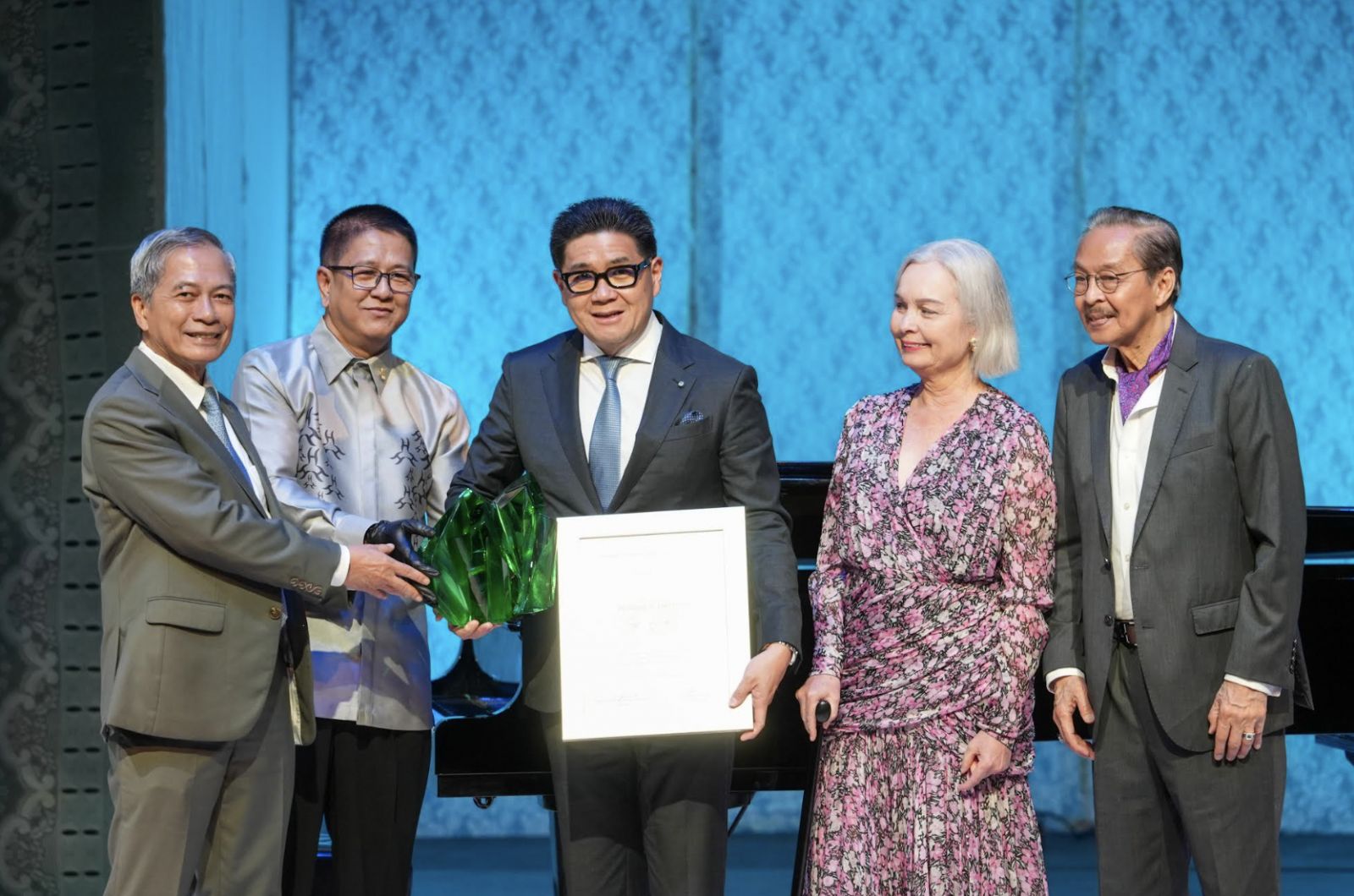 Anton Huang, receives an Orlina sculpture and plaque of recognition on behalf of his mother