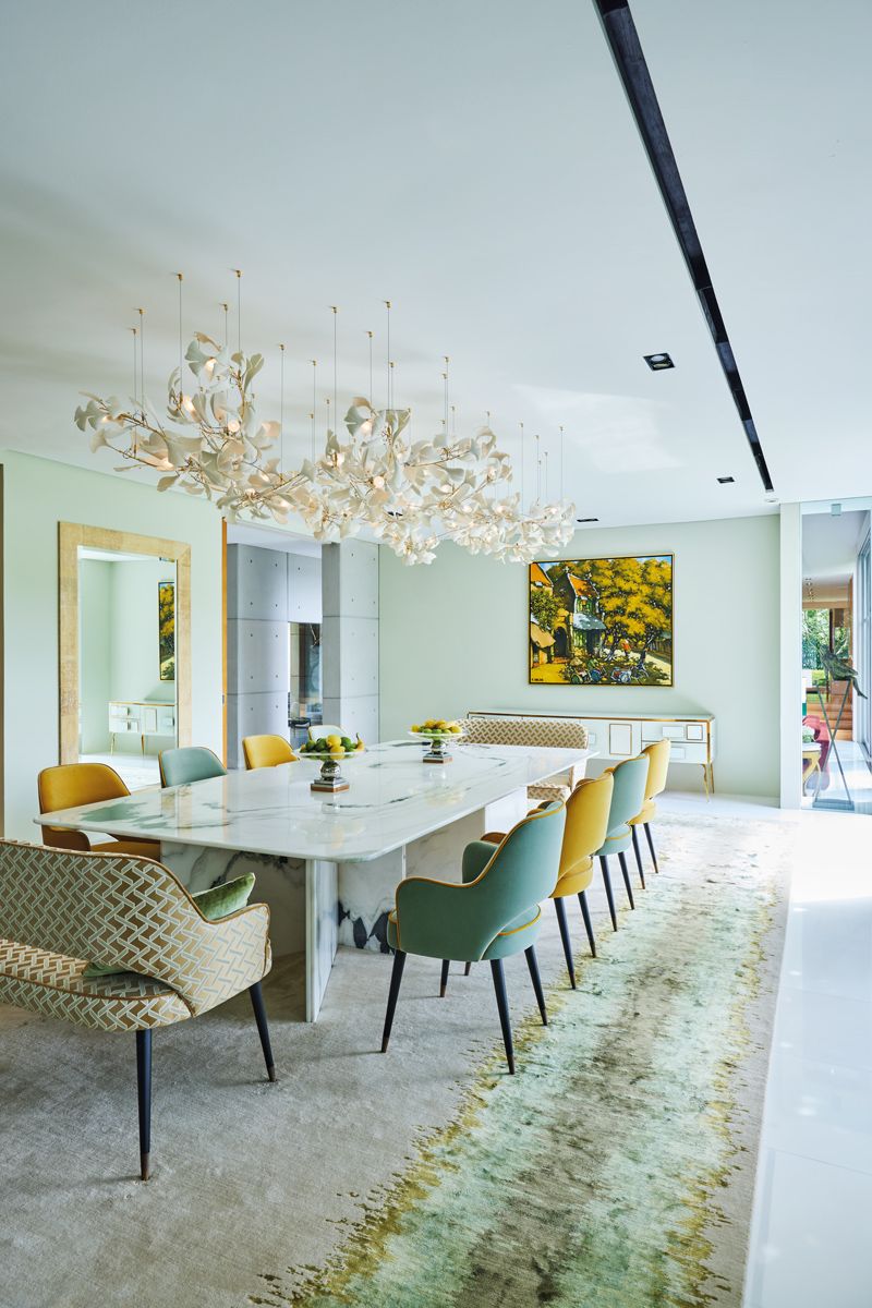 A Riviere rug and lighting installation by ceramic artist Andreea Braescu turn the dining room into a stunning extension of the landscape depicted in the painting hung at the head of the table