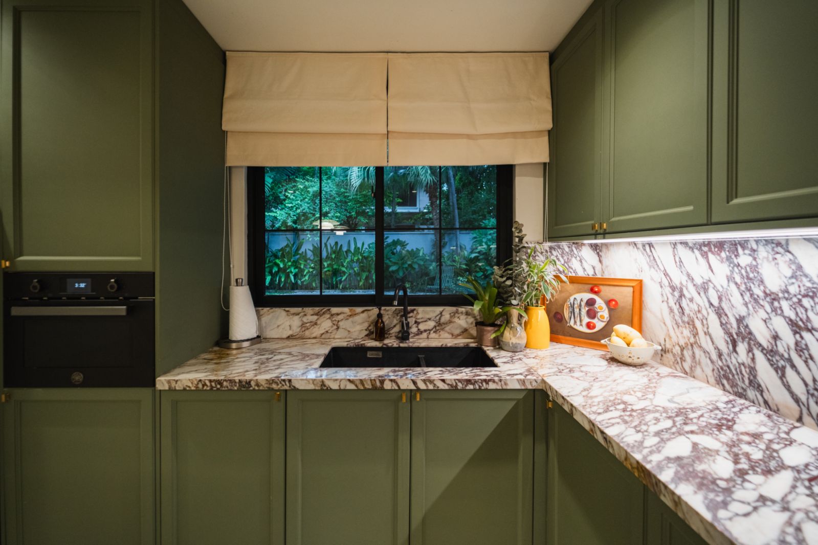 The kitchen, featuring Calacatta Viola marble countertops and green cabinets