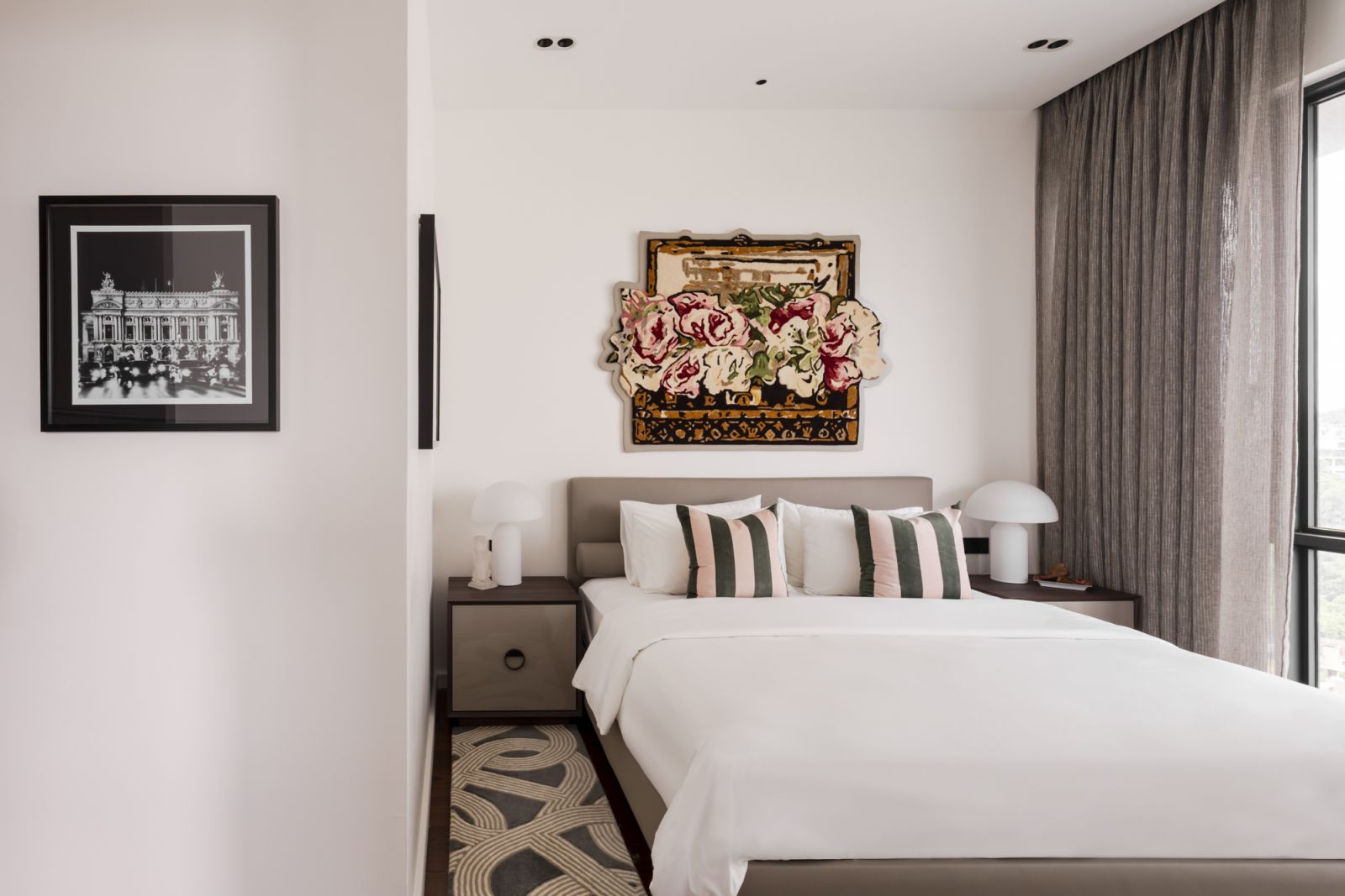 A custom headboard anchors the space, while curated black and white photography maintains the art gallery concept