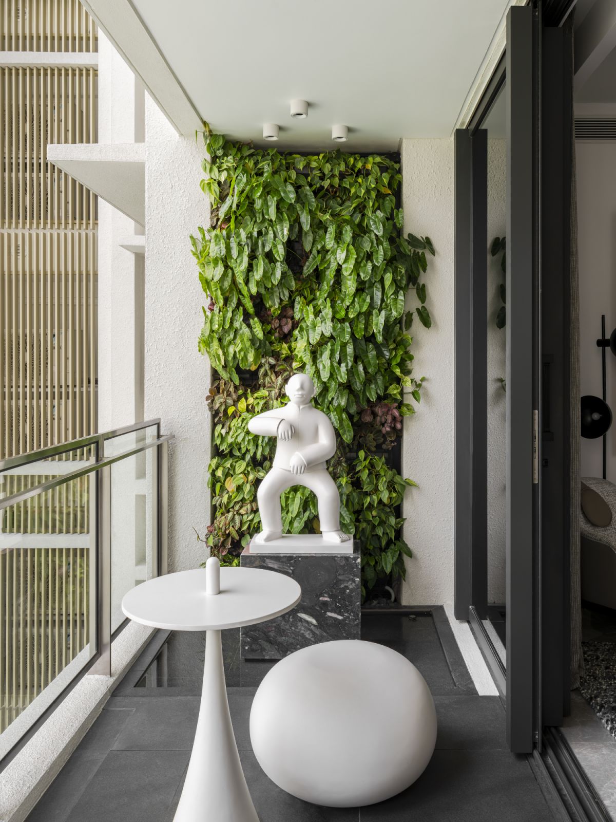 The balcony transforms into an artistic retreat with a striking white sculpture set against a lush green wall