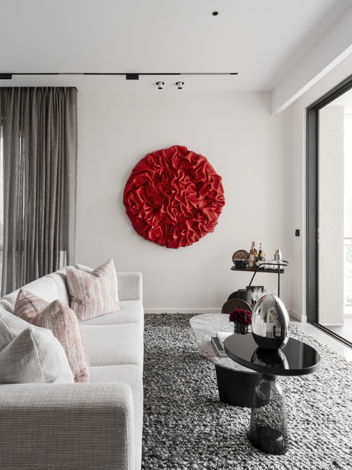 The sleek modern living room featuring a striking red circular wall sculpture as the centerpiece