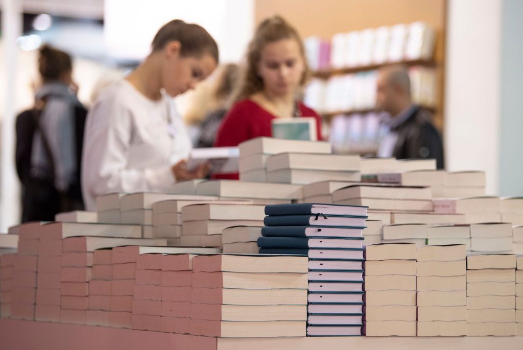 16 October 2019, Hessen, Frankfurt/Main: At the Frankfurt Book Fair, visitors leaf through a pile of new German-language publications. The Frankfurt Book Fair is considered the largest in the world. Photo: Boris Roessler/dpa (Photo by Boris Roessler/picture alliance via Getty Images)