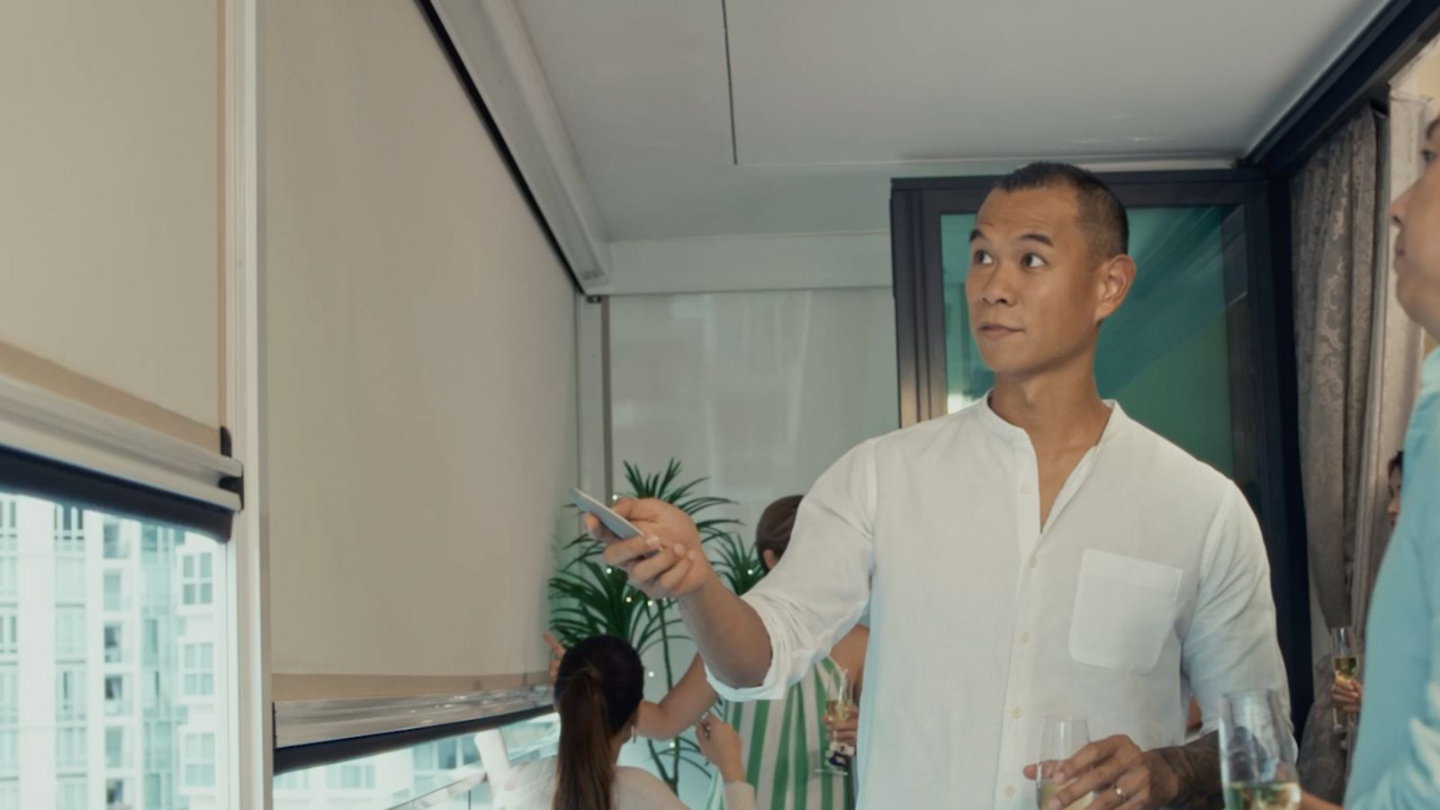 Homeowner Justin controlling the motorised Ziptrak Outdoor Blinds on his balcony in Singapore
