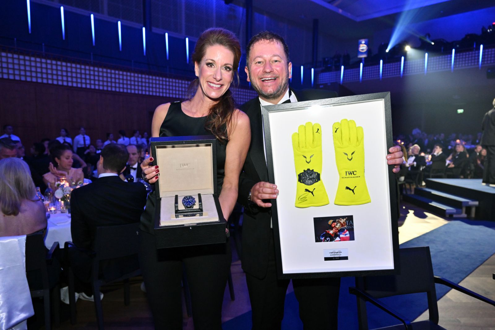 IWC Schaffhausen Chief Marketing Officer Franziska Gsell and Laureus AmDan Nicholl present Lewis Hamilton’s watch "Pilot’s Watch Performance Chronograph 41 Mercedes-AMG Petronas Formula One Team" bundled with signed racing gloves that are being auctioned during the Laureus Charity Night at Kongresshaus on October 19, 2024 in Zurich, Switzerland (Photo: Courtesy of IWC Schaffhausen)