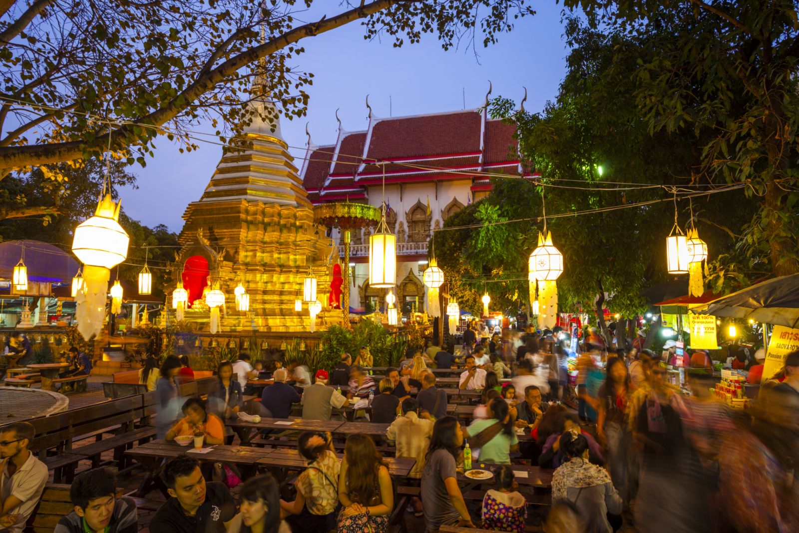 Many people sit at tables and eat at the market outside Wat Phra Singh on market night where many food stalls can be found within the temple courtyard, Chiang Mai, Thailand (Photo: Getty Images)