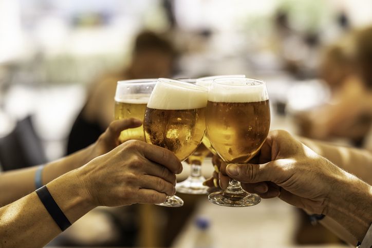Group of friends toasting with beer on the terrace during hot summer days.