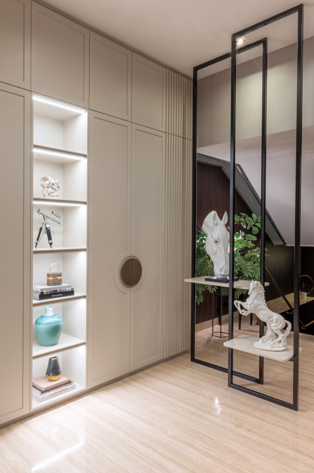 The elegant foyer, with its curated display of the homeowners’ treasured sculptures and other collectibles