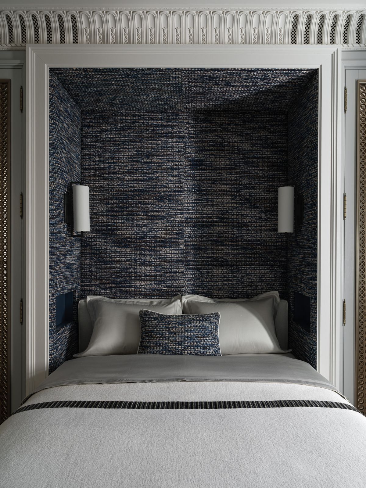 One of the bedrooms, with a cosy, textured alcove upholstered in deep blue fabric