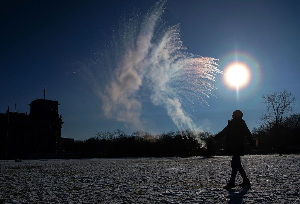 31 January 2021, Berlin: On the lawn in front of the Reichstag, a man hurls boiling water from a bottle into the air, which immediately freezes in the sub-zero temperatures. Photo: Paul Zinken/dpa-Zentralbild/ZB (Photo by Paul Zinken/picture alliance via Getty Images)