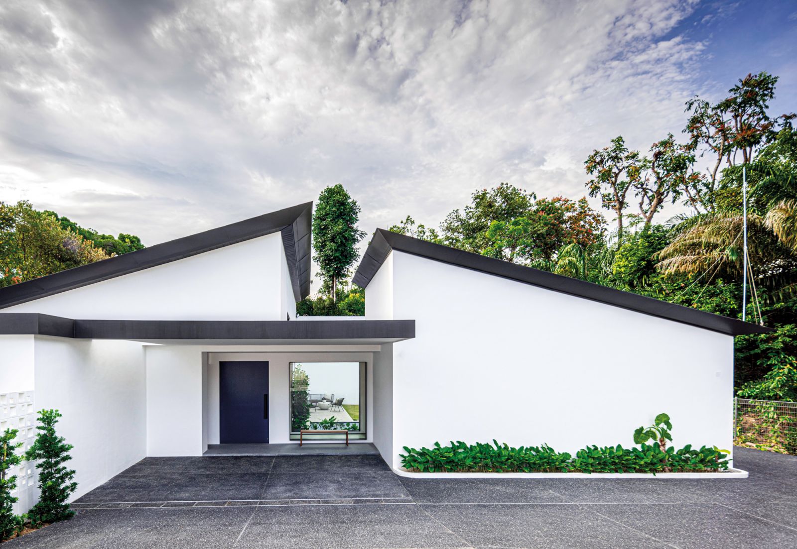 Grey steel roofing lends a graphic edge to the house’s clean white facade