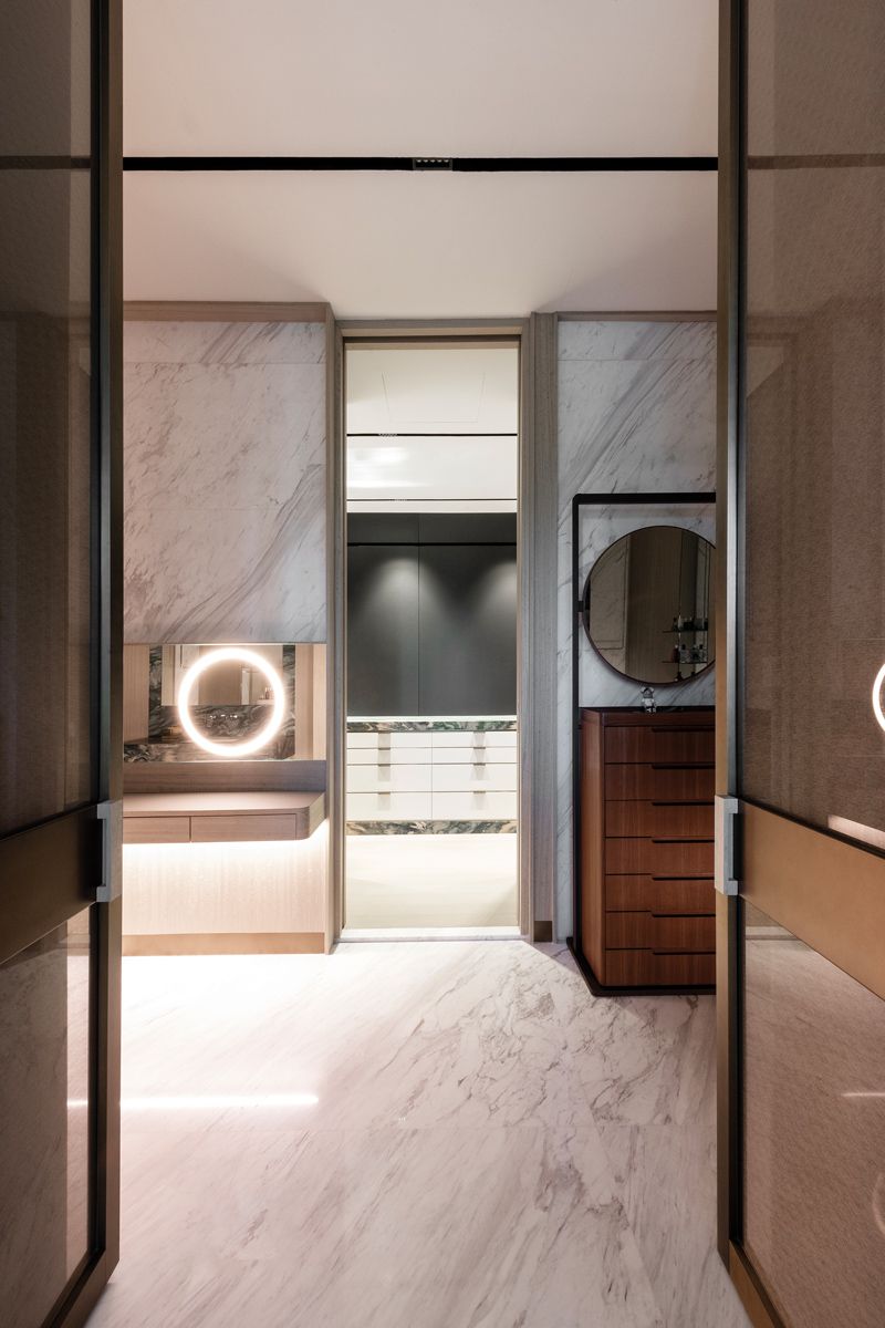 This vanity area is clad in delicately veined white marble and features furnishings with circular elements
