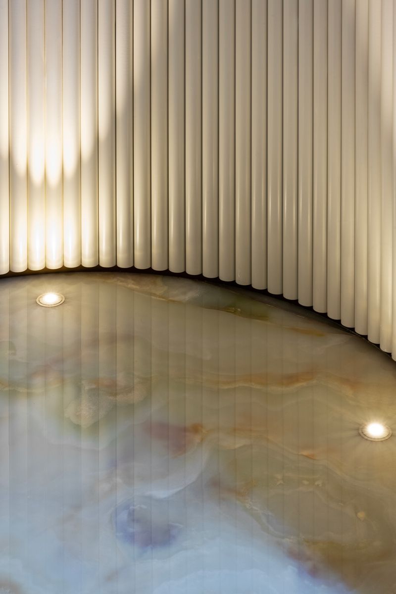 A close-up detail of the powder room's green onyx floor and fluted wall