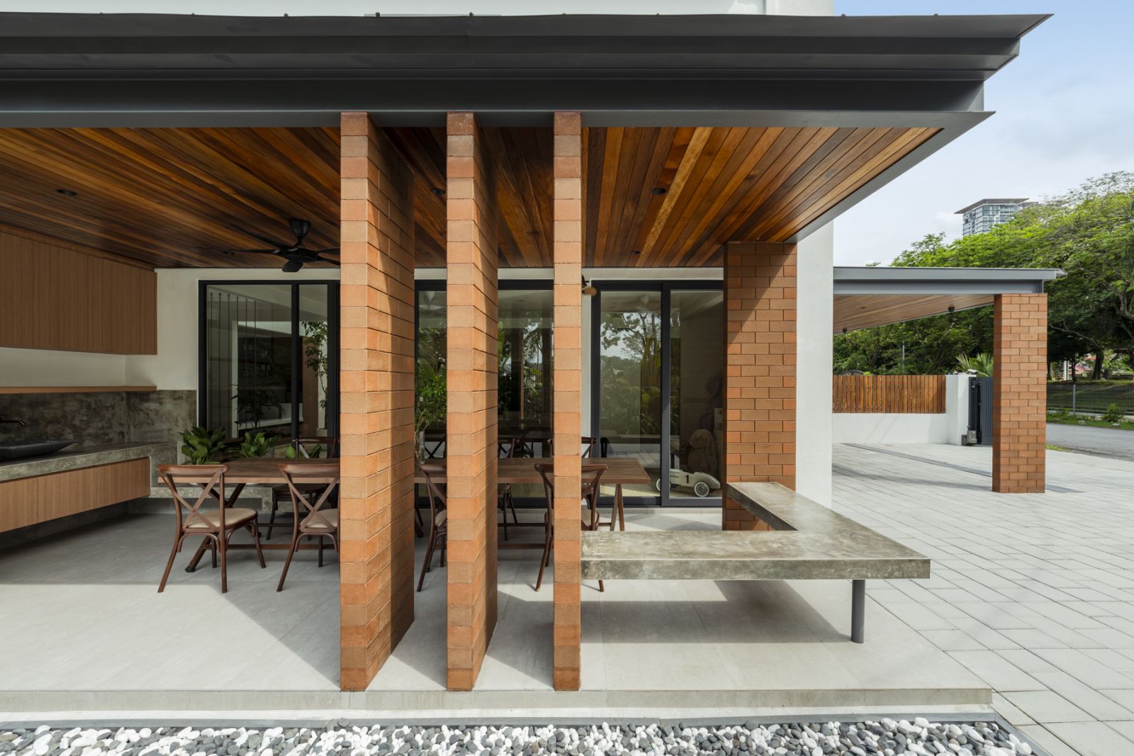 The covered terrace showcases the architect’s innovative use of compressed earth brick columns and Balau wood ceiling panels