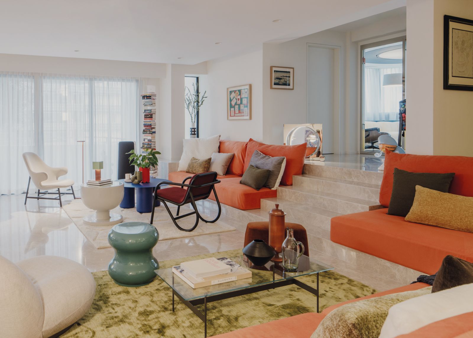 Orange upholstery lends freshness to the sunken living space in this artistic home