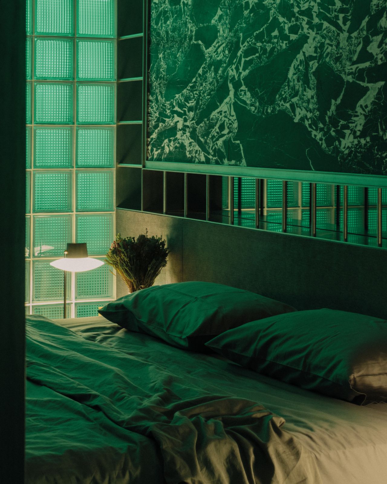 The glass-block wall that separates the sleeping zone and the bathroom takes on the colour-changing light, shown here in green