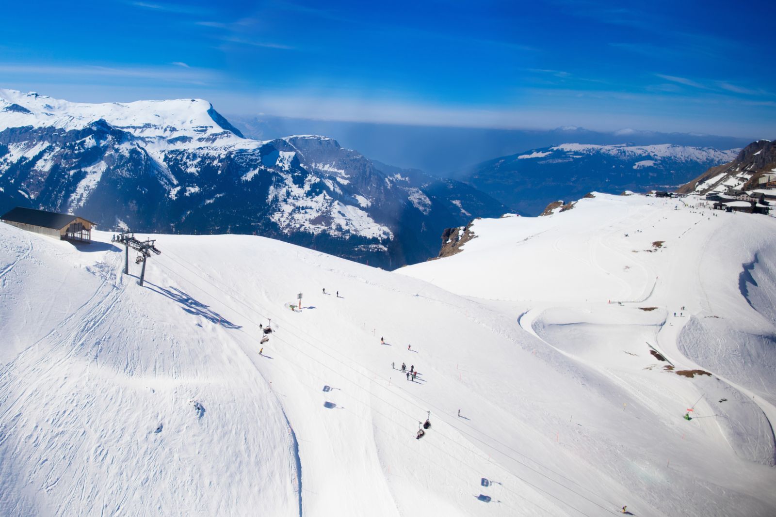 Aerial view of the Alps mountains in Switzerland. View from helicopter above glacier in Swiss Alps. Mountain tops covered in snow. Alpine ski facilities from above.