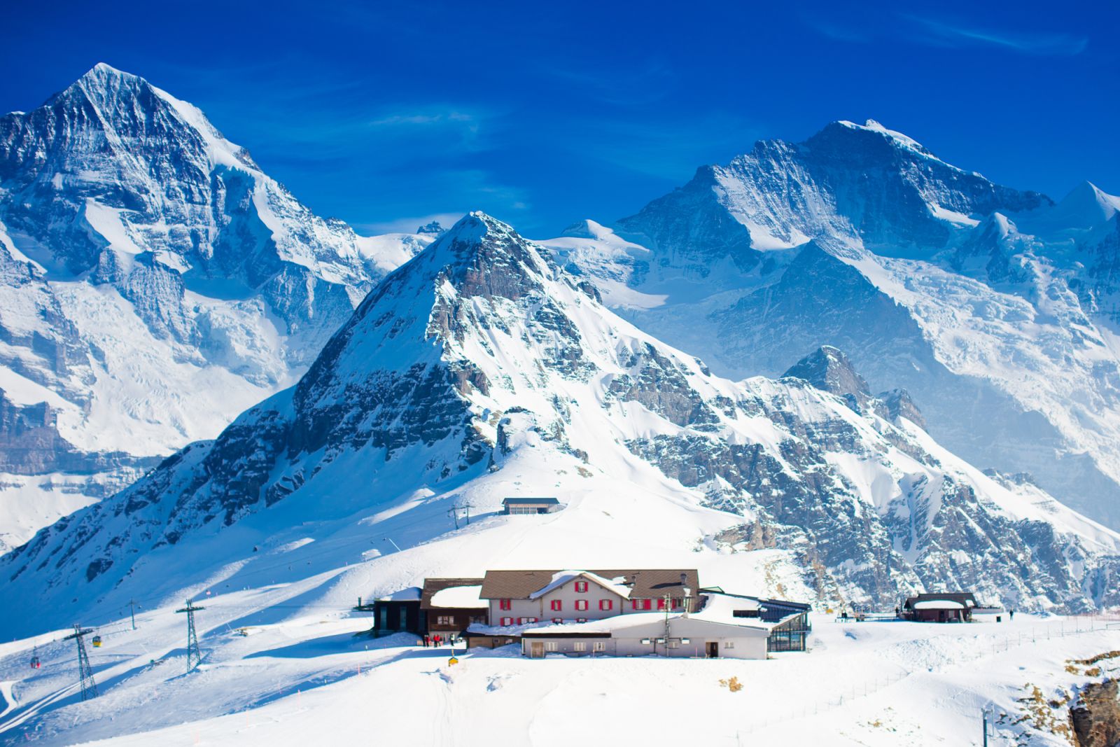 Aerial view of the Alps mountains in Switzerland. View from helicopter above glacier in Swiss Alps. Mountain tops covered in snow. Alpine ski facilities from above.