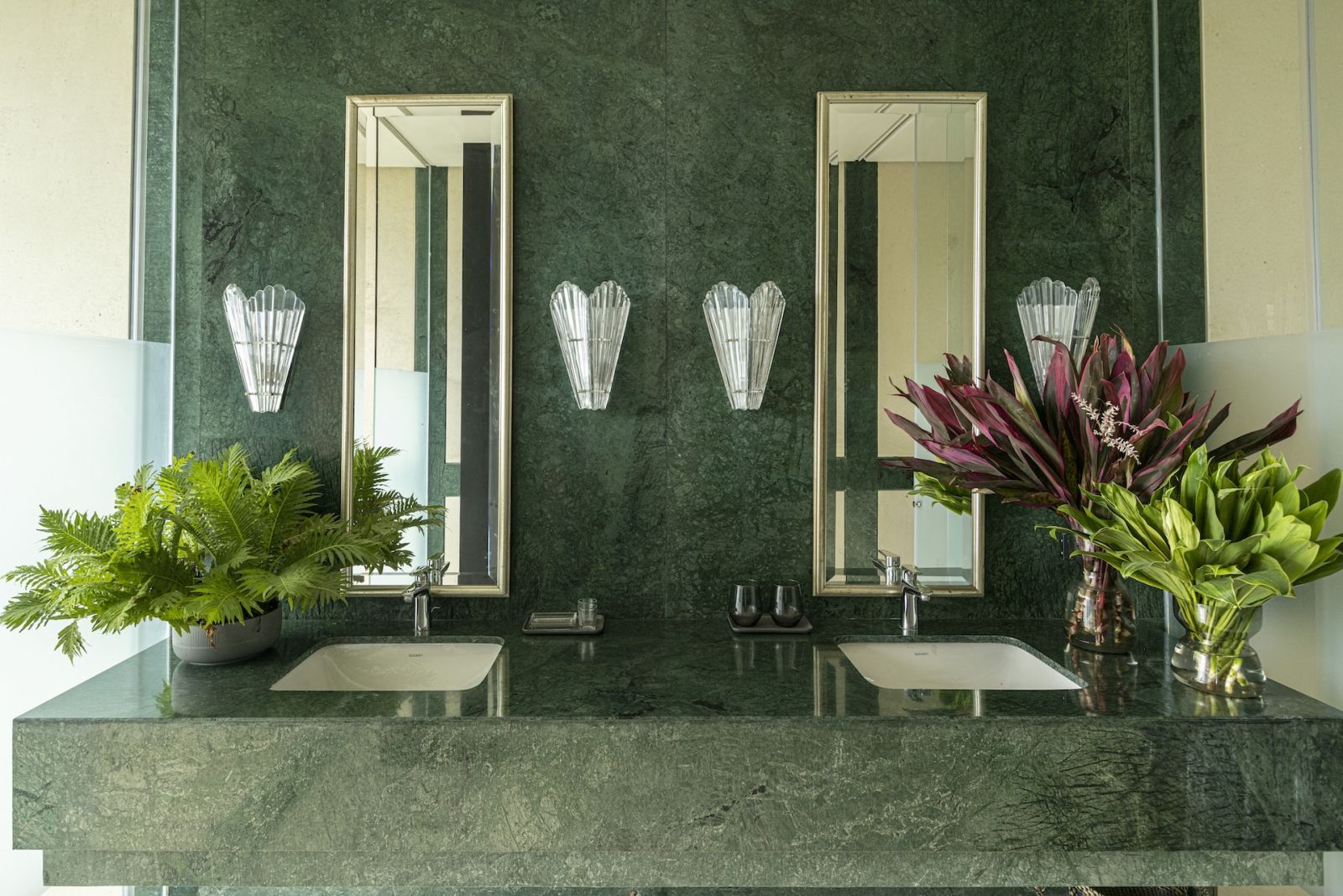 The guest bathroom, with green marble that mirrors the lush plants outside