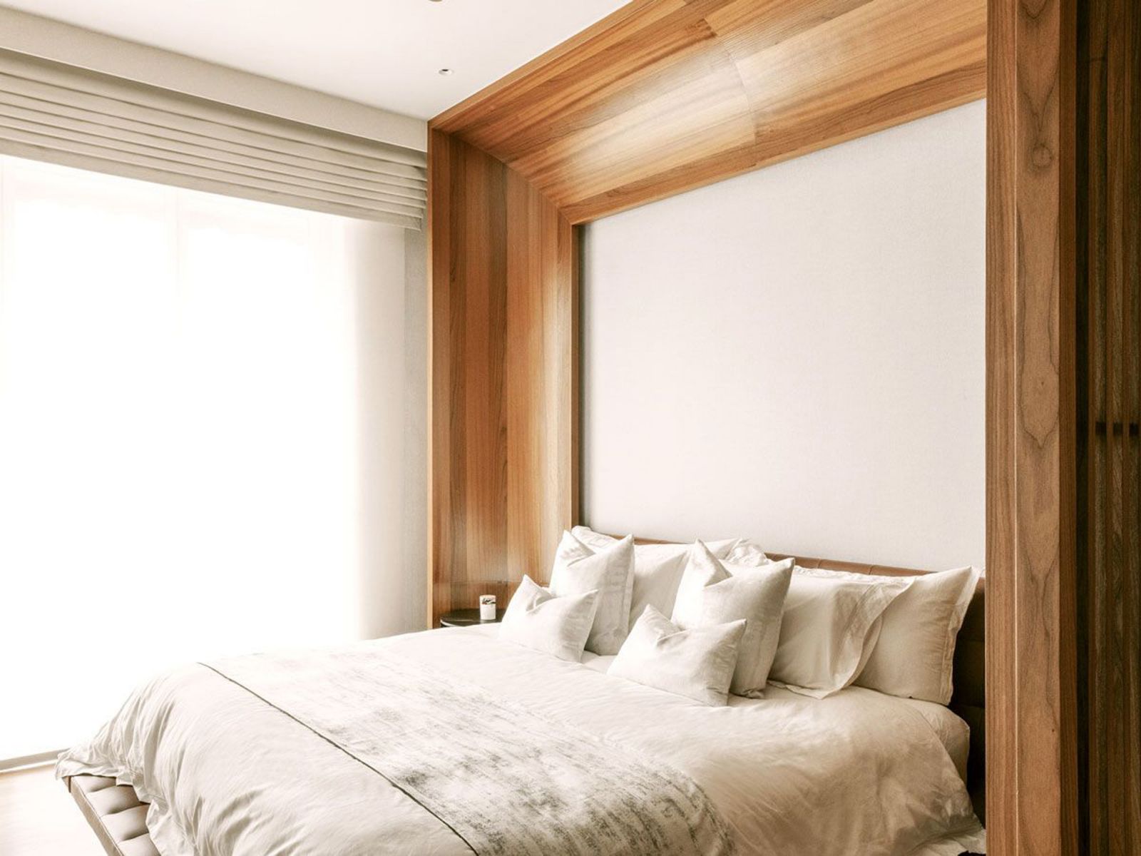 The wooden portal that frames the bed is reminiscent of the design of yacht cabins