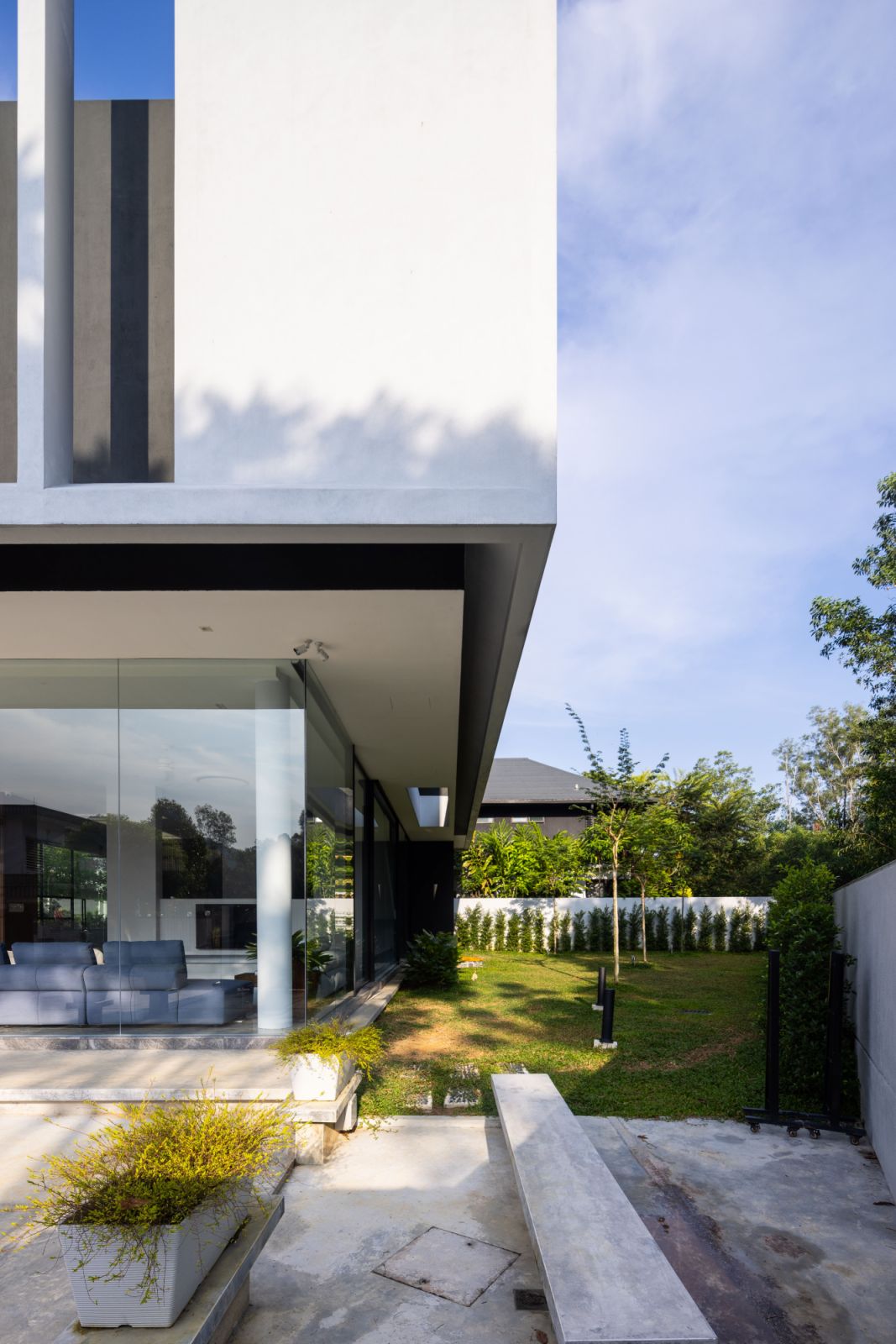 The angular plot's largest section has been transformed into a landscaped entertainment space that seamlessly connects with the interior through transparent walls