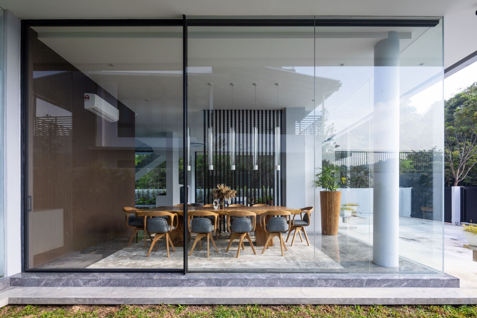 The landscaped entertainment space seamlessly connects with the interior through transparent walls