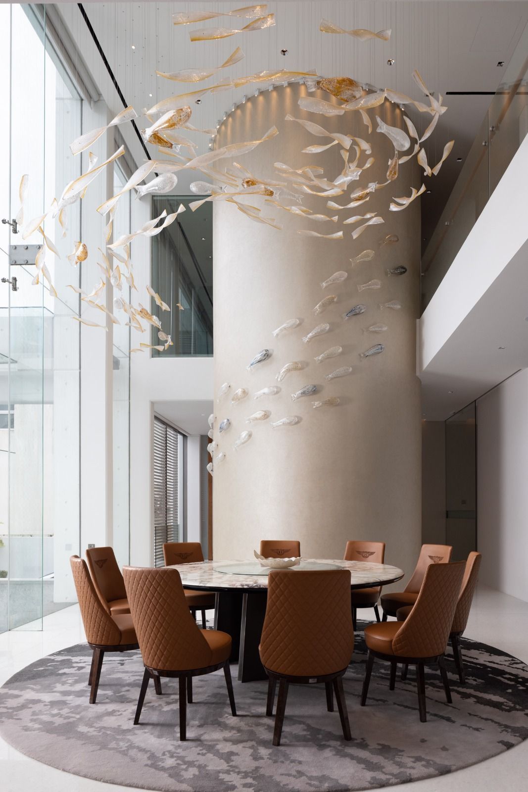 A custom glass installation created in collaboration with SpectraOne floats above the Bentley Harlette swivel dining chairs and Visionnaire Jason dining table