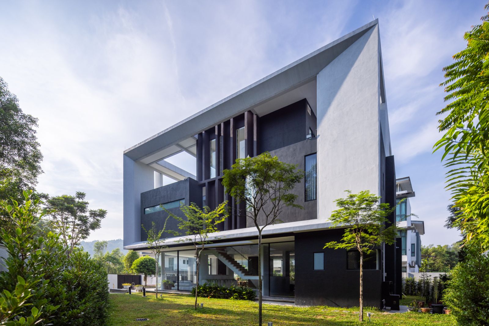 The angular plot's largest section has been transformed into a landscaped entertainment space that seamlessly connects with the interior through transparent walls