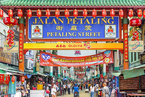 Kuala Lumpur, Malaysia: Crowds pass below the main gate of Chinatown at Petaling Street.