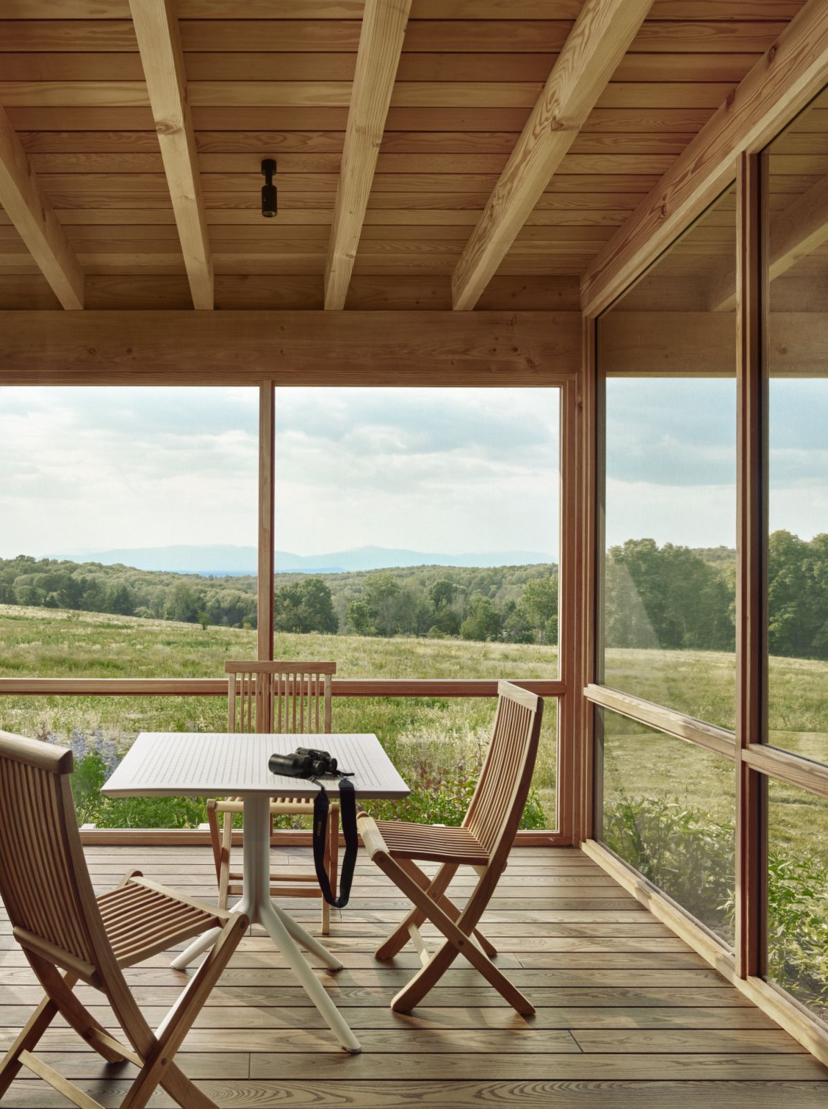 The screened in porch, with views of the meadow outside the home