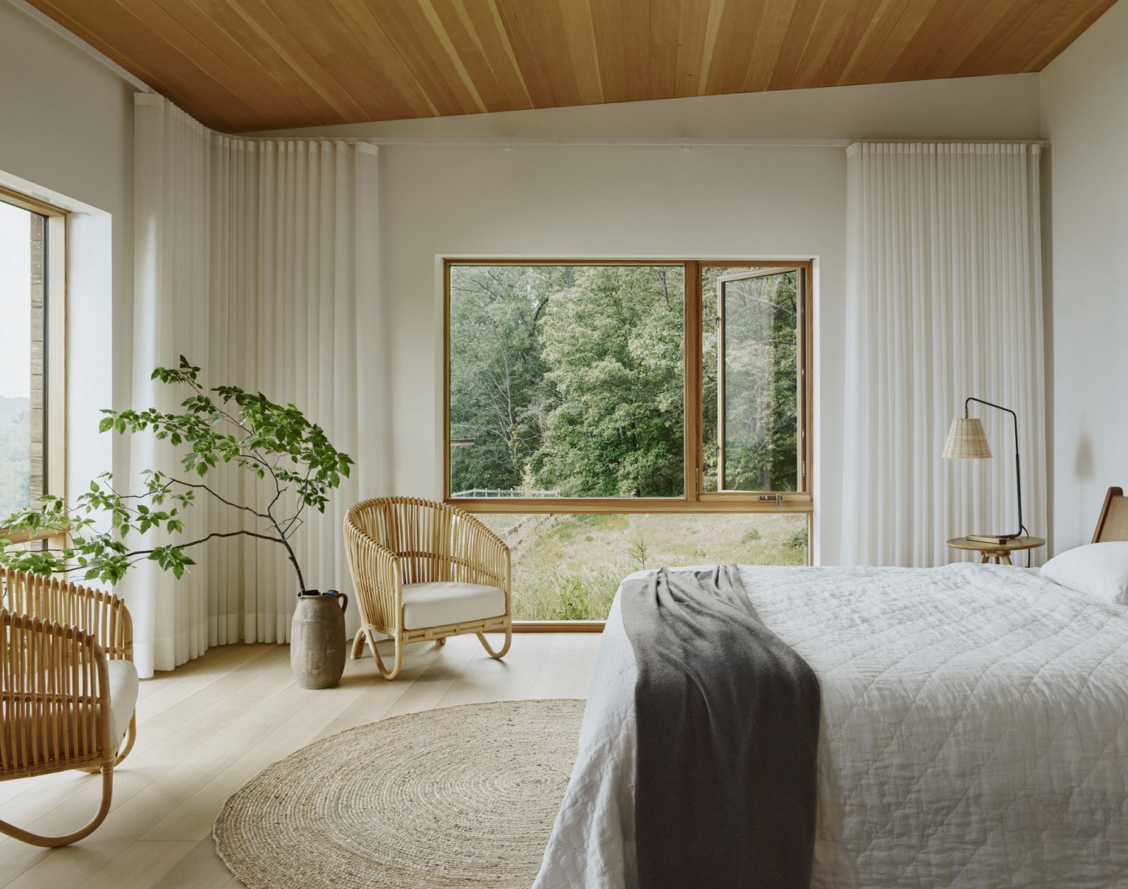 A glimpse of the primary bedroom, with views of the nearby forest