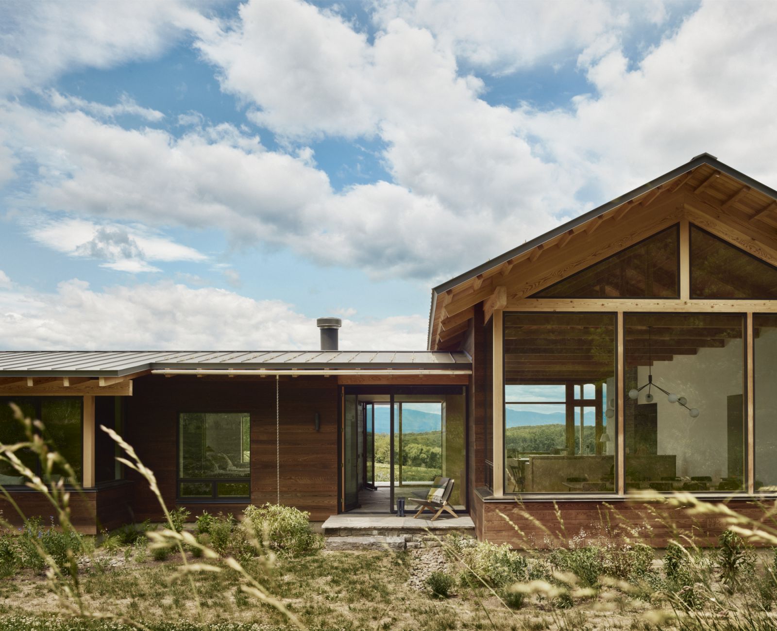 An exterior shot of the Hudson Valley home, with clear blue skies complementing the warm wood