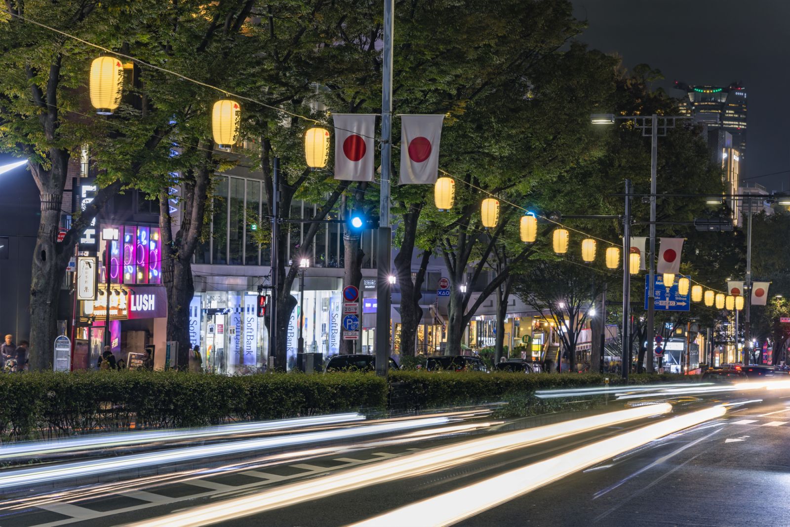 tokyo, japan - november 05 2019: Cars headlights driving at night on the Omotesando avenue called also Champs-Élysées adorned with illuminated paper lanterns and national flag of Japan called Hinomaru