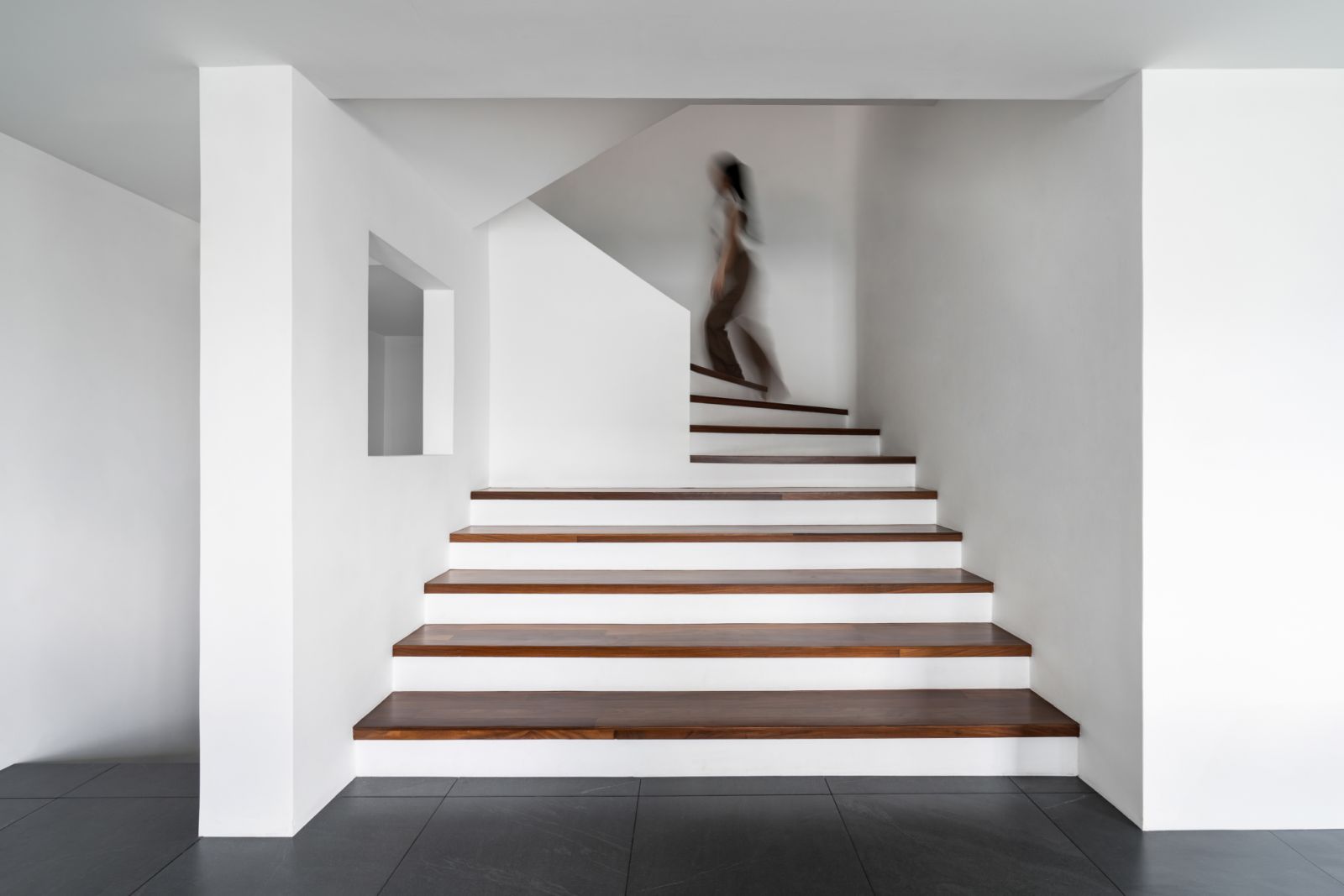 Dark tiles and wooden steps create a sophisticated contrast against the white walls