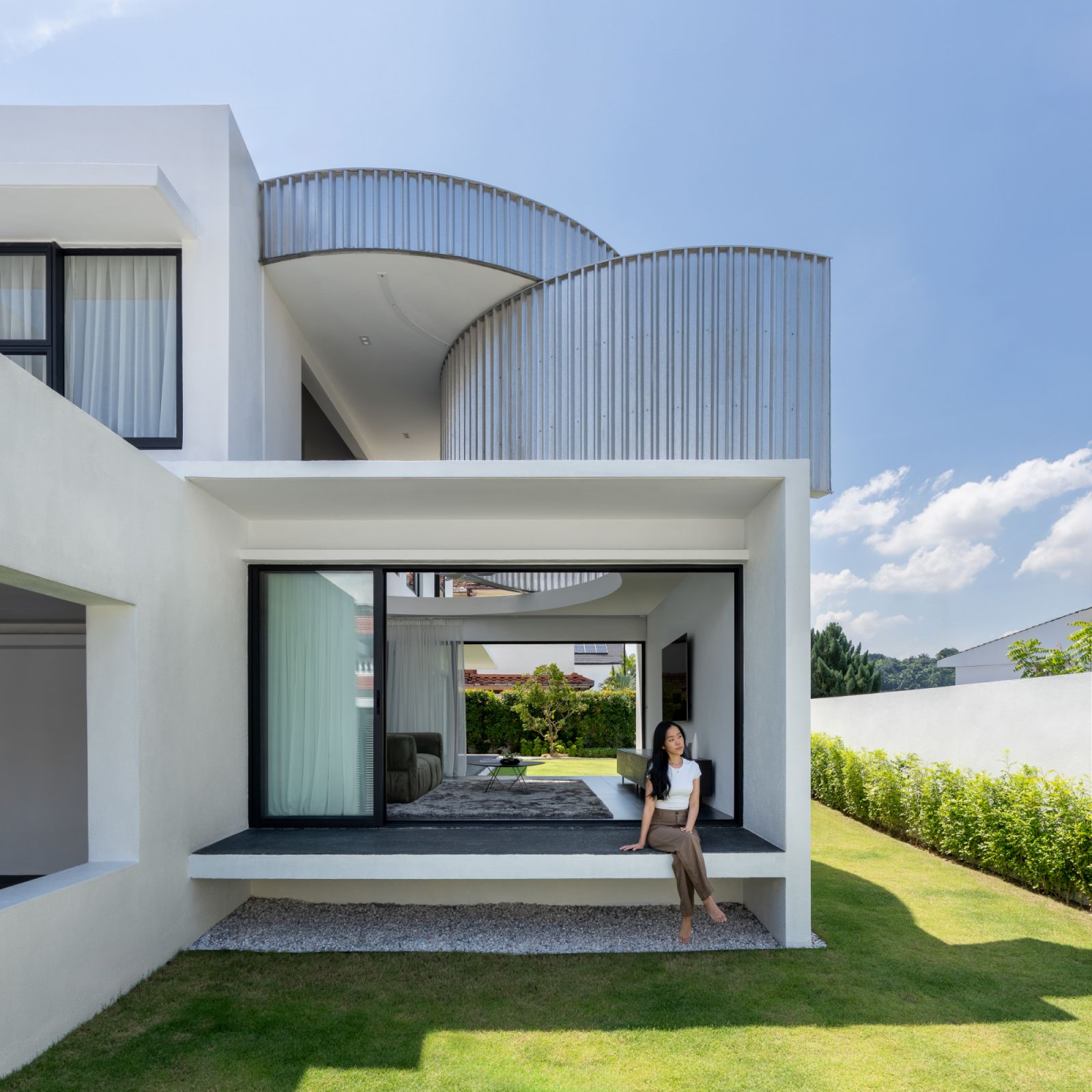 Landscaping frames the contemporary white facade, creating a harmonious blend of natural and architectural elements