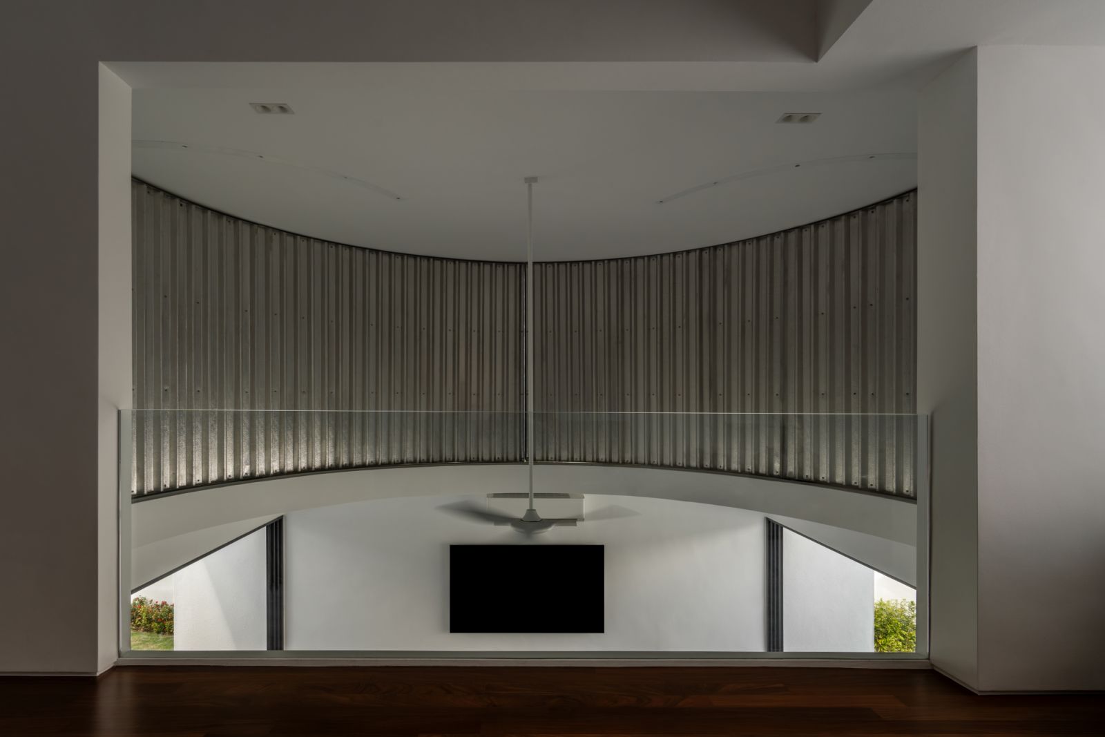 The double-volume living room’s signature feature: the curved corrugated metal wall that forms the ‘moon doors’, framing triangular glimpses of the garden