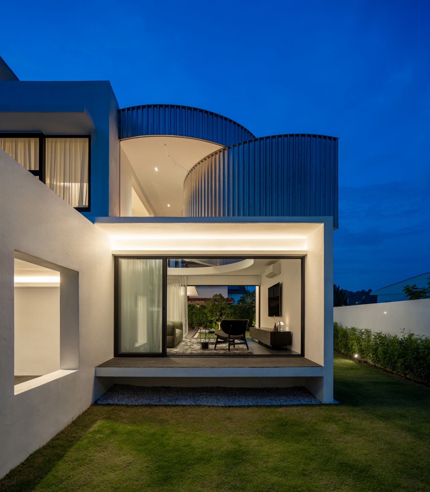 The CC House glows at dusk, with its signature cylindrical metal features illuminated against the purple-blue twilight sky