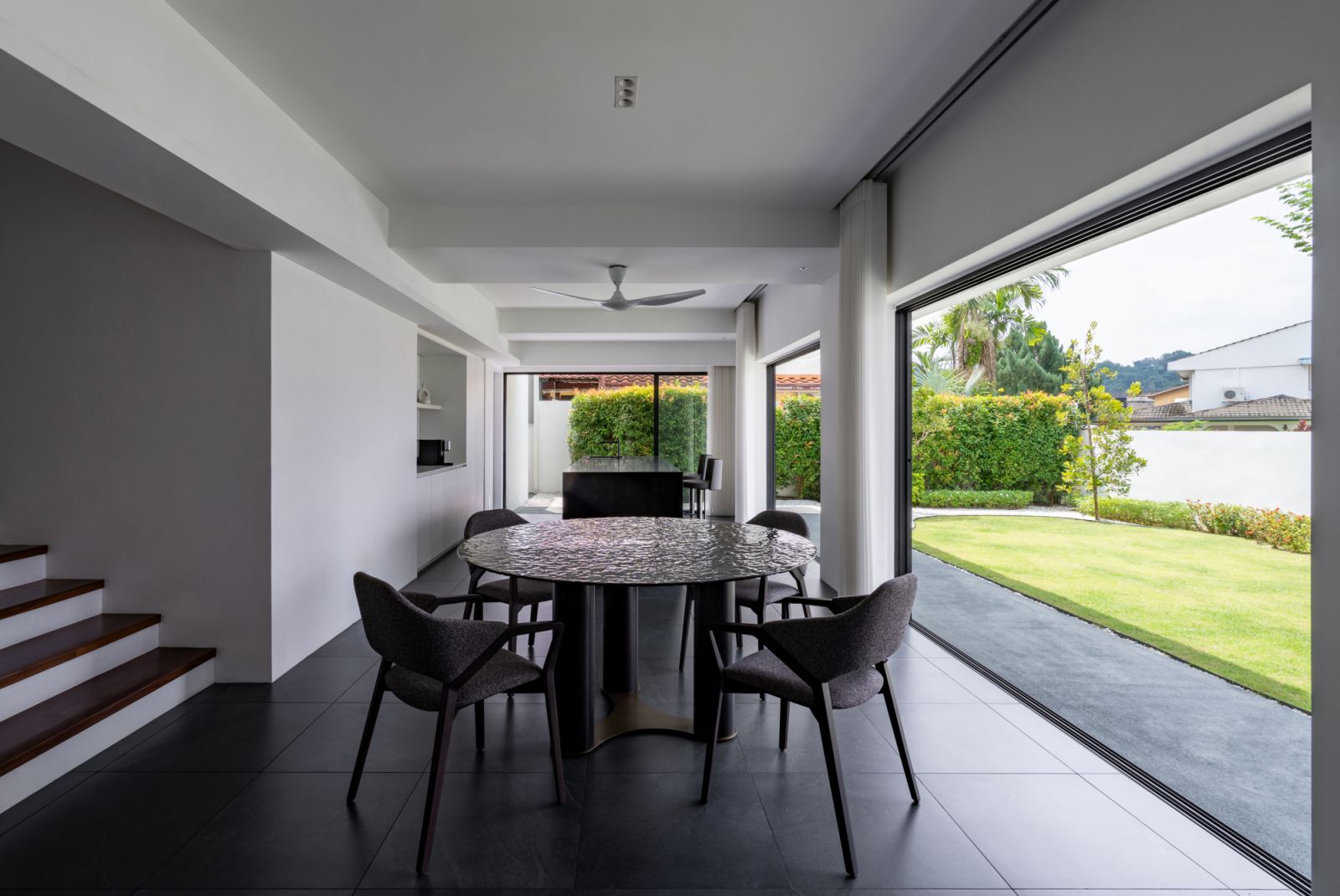 The open-plan dining area seamlessly connects to the garden through floor-to-ceiling sliding glass doors