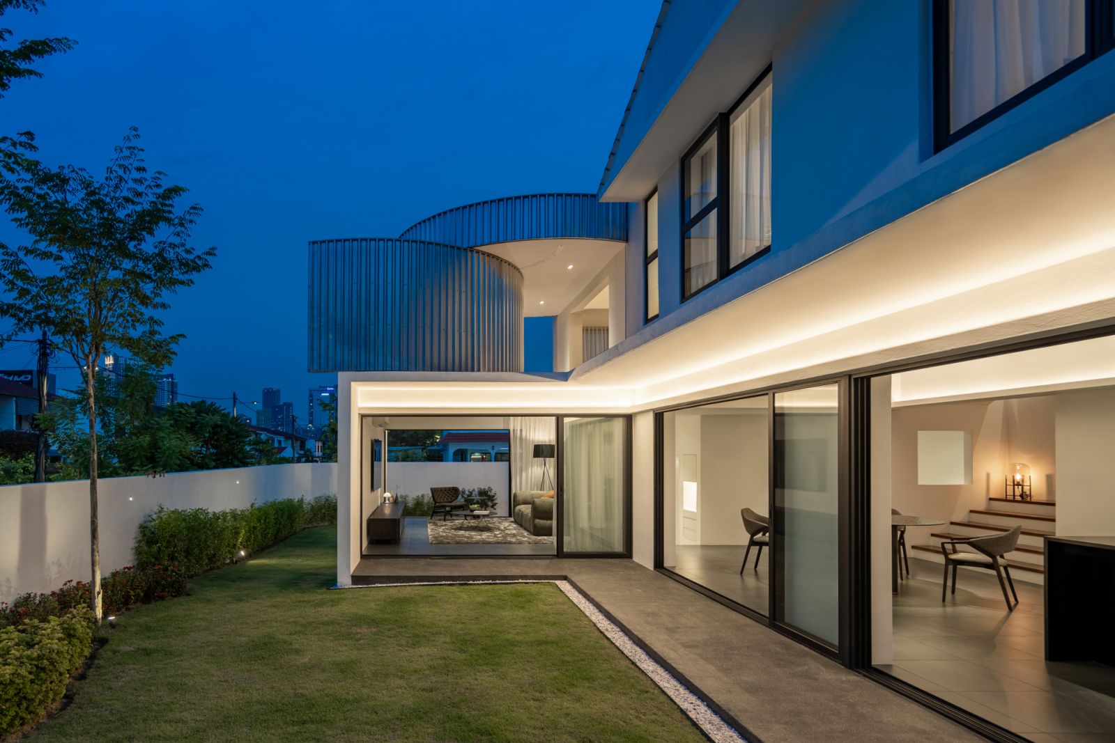 The CC House glows at dusk, with its signature cylindrical metal features illuminated against the purple-blue twilight sky