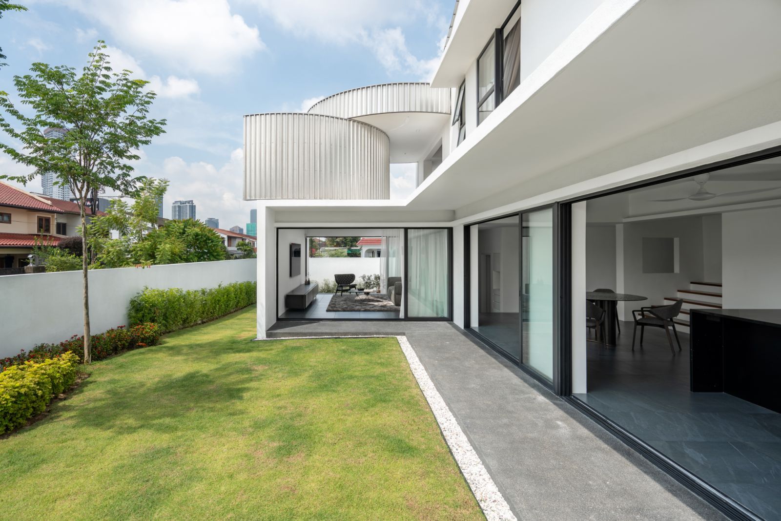 Floor-to-ceiling sliding glass doors open to a manicured garden, showcasing the house’s seamless indoor-outdoor flow