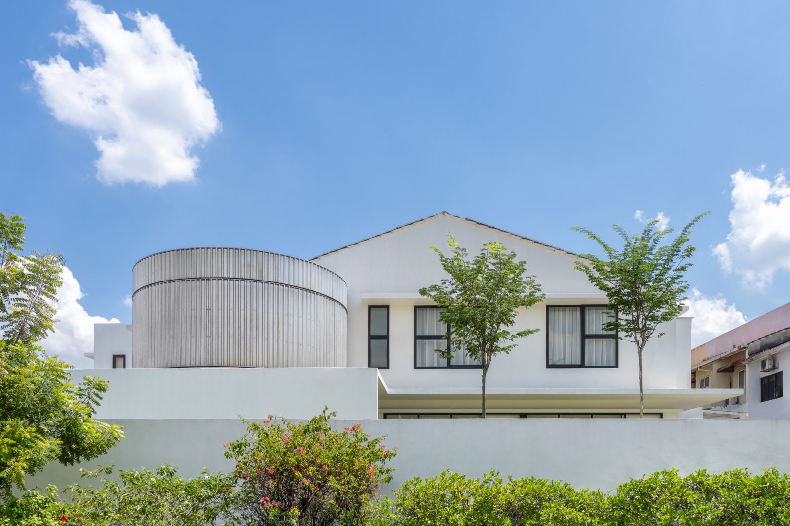 The curved metal facade creates an intimate seating area, demonstrating how the house responds to both urban context and personal comfort