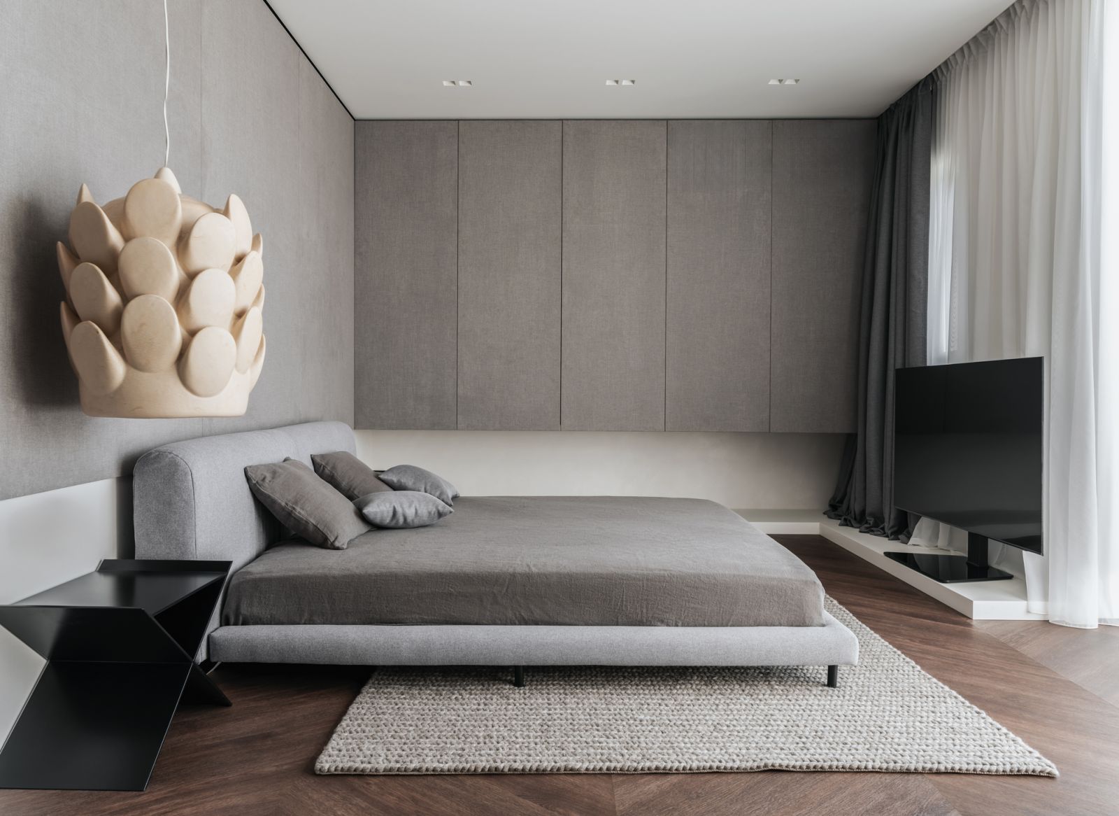 A sculptural statement pendant lamp is a highlight in this otherwise minimalist bedroom
